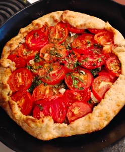 freeform pastry in a black skillet, filled with sliced tomatoes